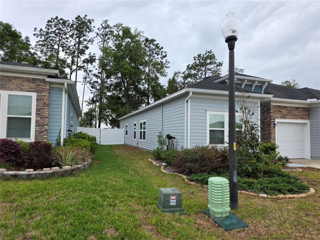 A view of the side yards and exterior of two light blue suburban houses — 7875 SW 74TH LOOP, OCALA, FL