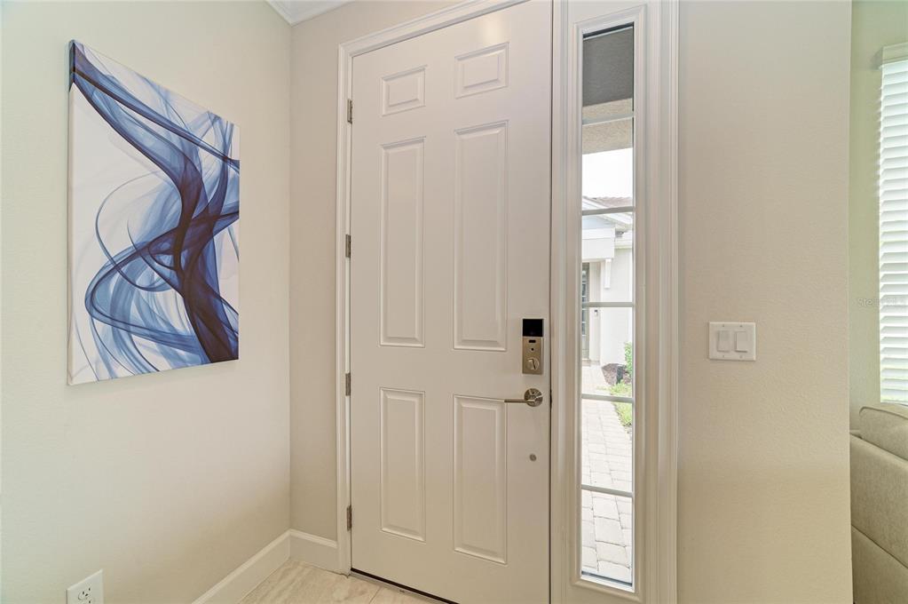 A white front door with a side window and abstract wall art in an entryway — 16112 ISOLA PLACE, BRADENTON, FL