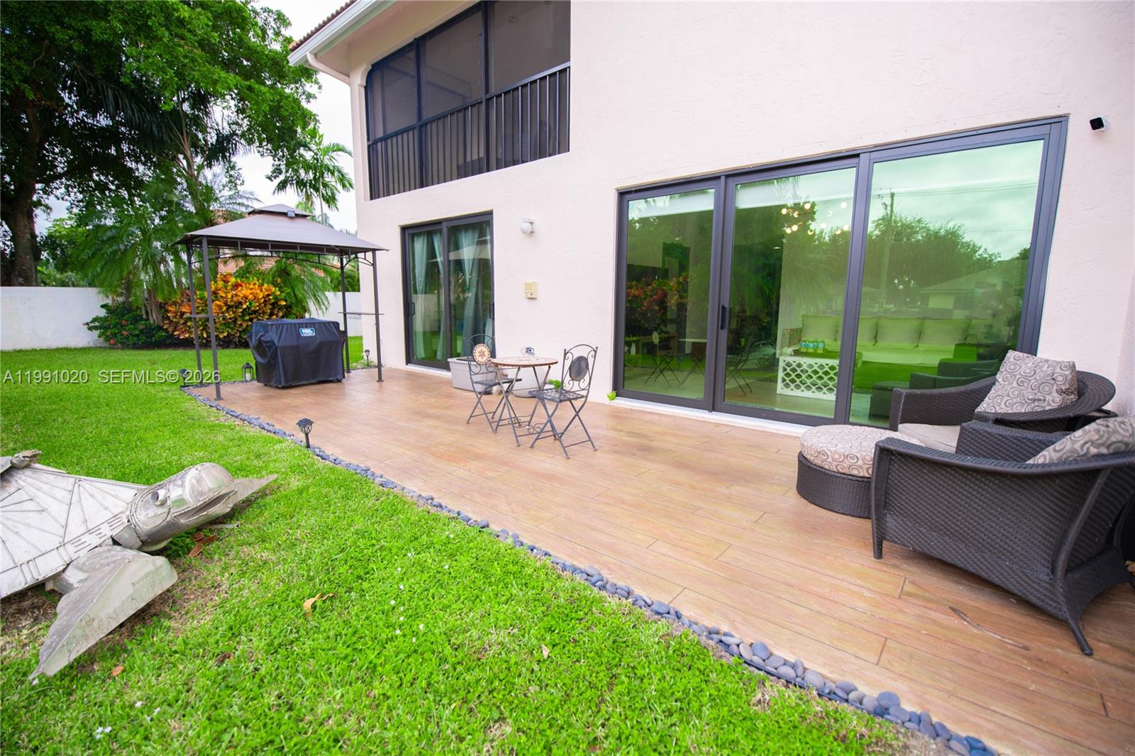 A patio with wood-look tile flooring features outdoor furniture, a grill, and sliding glass doors — 8694 Via Reale # 3, Boca Raton FL 33496, BOCA RATON, FL