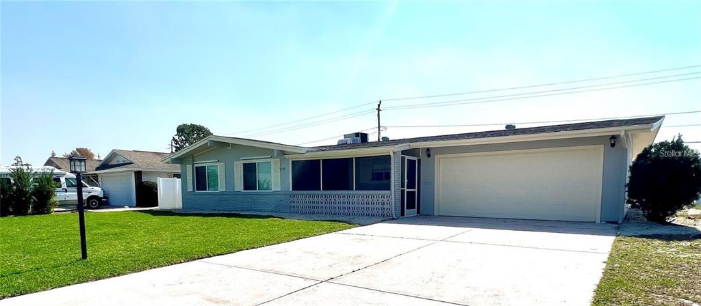 A light-colored single-story house features a large garage and a screened-in front porch — 912 LA JOLLA AVENUE, SUN CITY CENTER, FL