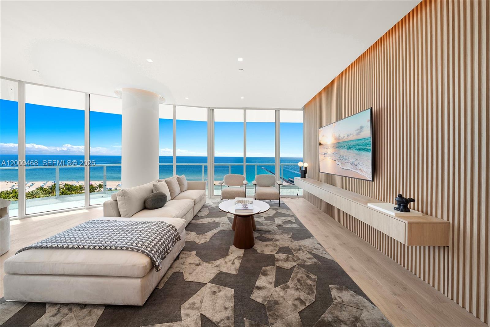 A modern living room features floor-to-ceiling windows, a slatted wood wall, and ocean views — 100 S Pointe Dr # 1206, Miami Beach FL 33139, MIAMI BEACH, FL
