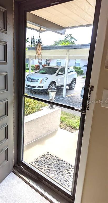 A view through a glass storm door looking out at a parked white SUV — 802 CORDOVA GREEN UNIT 802, SEMINOLE, FL
