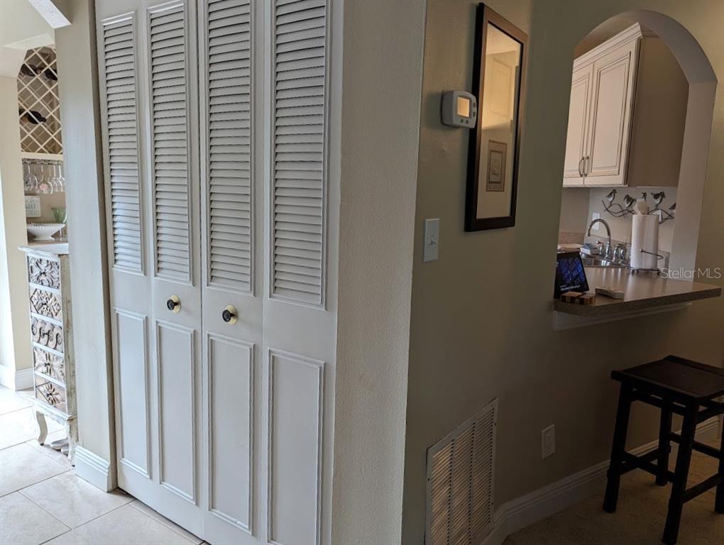 A view of a hallway with louvered closet doors, a thermostat, and a kitchen pass-through — 802 CORDOVA GREEN UNIT 802, SEMINOLE, FL