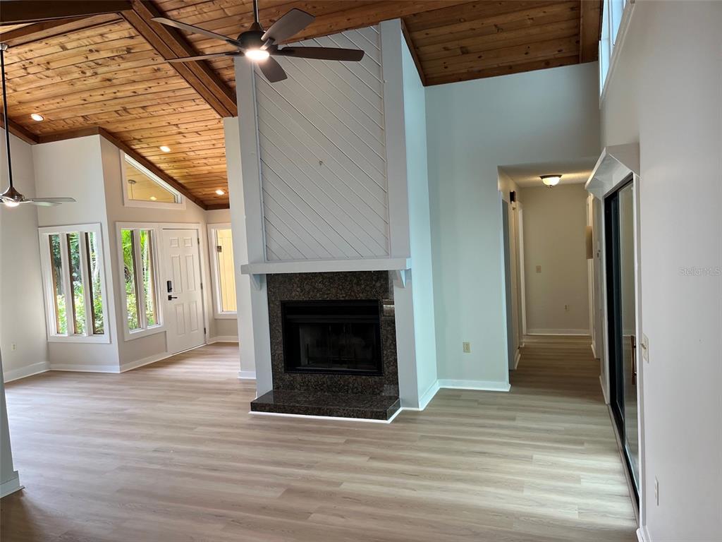 A living room features a wood-paneled vaulted ceiling, a fireplace, and light-colored wood flooring — 7518 4TH AVENUE W, BRADENTON, FL