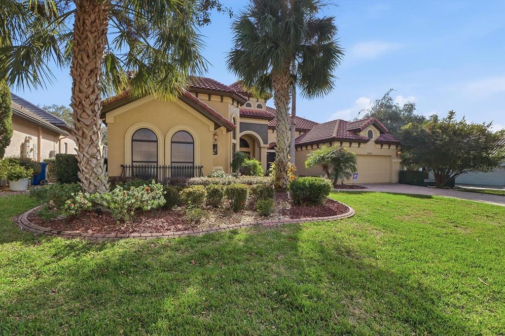 A tan stucco house with a tiled roof and palm trees in the front yard — 1416 N RIDGE MEADOW PATH, HERNANDO, FL