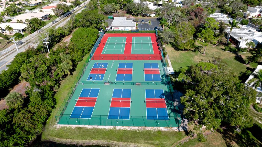 An aerial view of a fenced outdoor sports complex featuring multiple pickleball courts — 146 WILD PALM DR UNIT 146, BRADENTON, FL