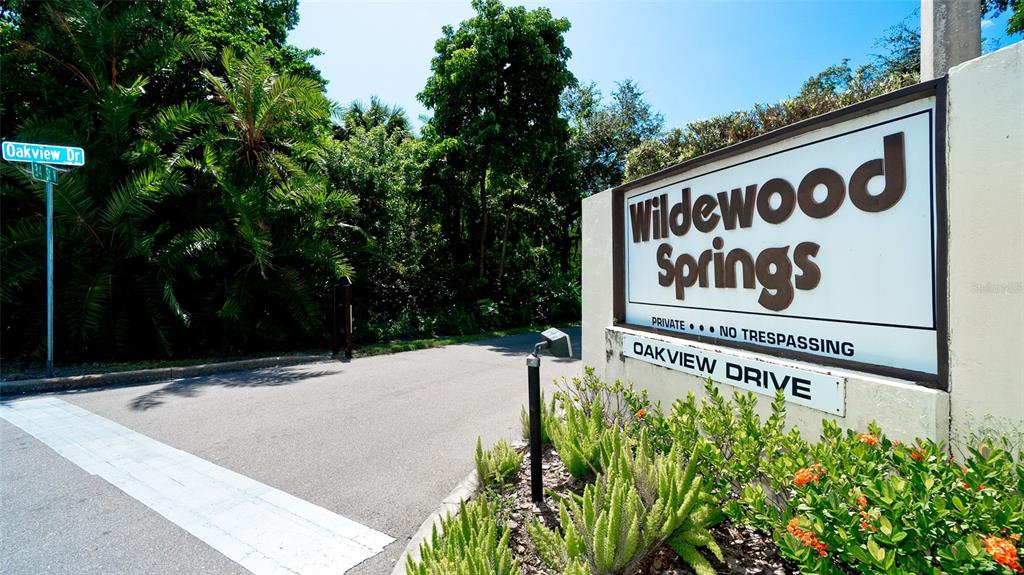 A sign for Wildewood Springs stands at the entrance to a paved road — 146 WILD PALM DR UNIT 146, BRADENTON, FL