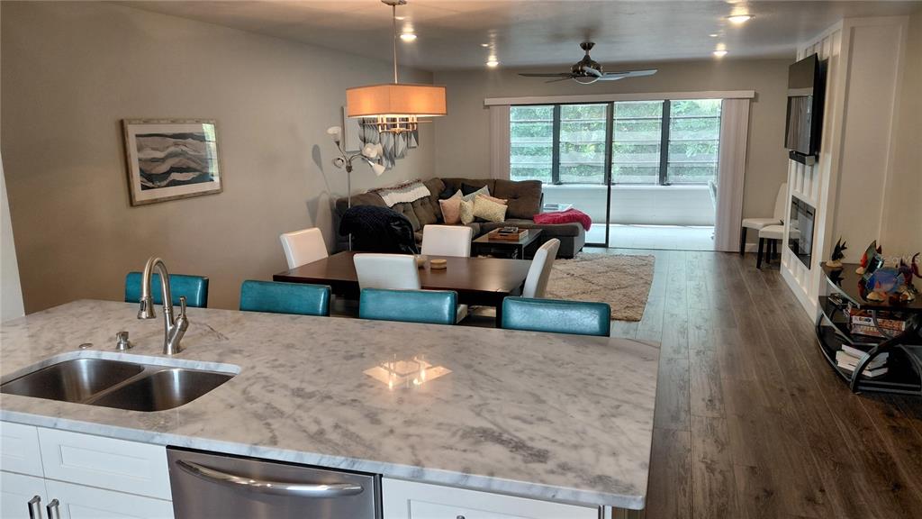 A kitchen island with a marble countertop overlooks an open-concept dining and living area — 146 WILD PALM DR UNIT 146, BRADENTON, FL