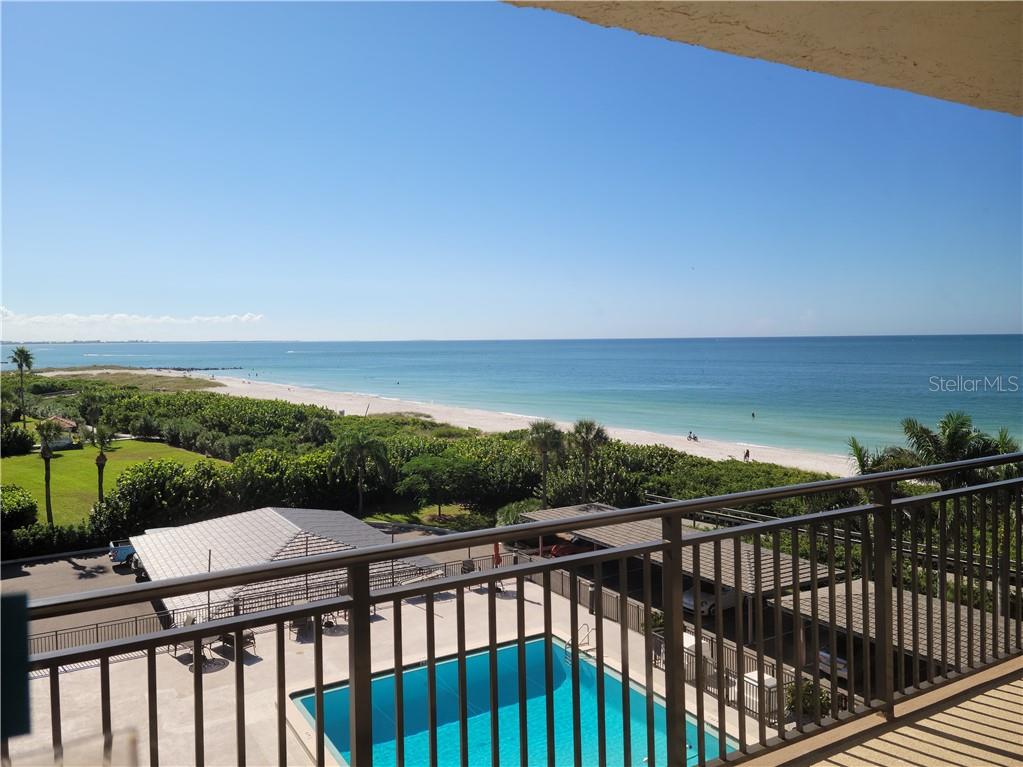 A balcony view overlooking a swimming pool, lush vegetation, a sandy beach, and the ocean — 7650 BAYSHORE DRIVE UNIT 401, TREASURE ISLAND, FL