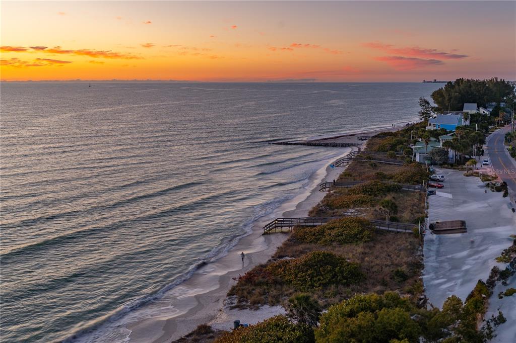 An aerial view of a sunset over a beach with wooden walkways and coastal vegetation — 7650 BAYSHORE DRIVE UNIT 401, TREASURE ISLAND, FL