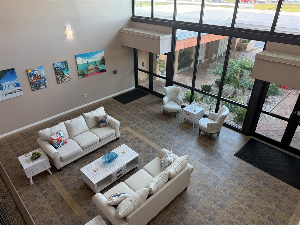 A high-angle view of a lobby featuring two sofas, armchairs, and large floor-to-ceiling windows — 2290 AARON STREET UNIT 101, PORT CHARLOTTE, FL