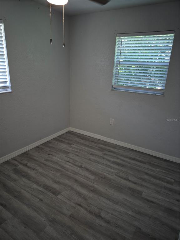 An empty bedroom features gray walls, wood-look flooring, and two windows with white blinds — 321 JERU BOULEVARD UNIT C, TARPON SPRINGS, FL