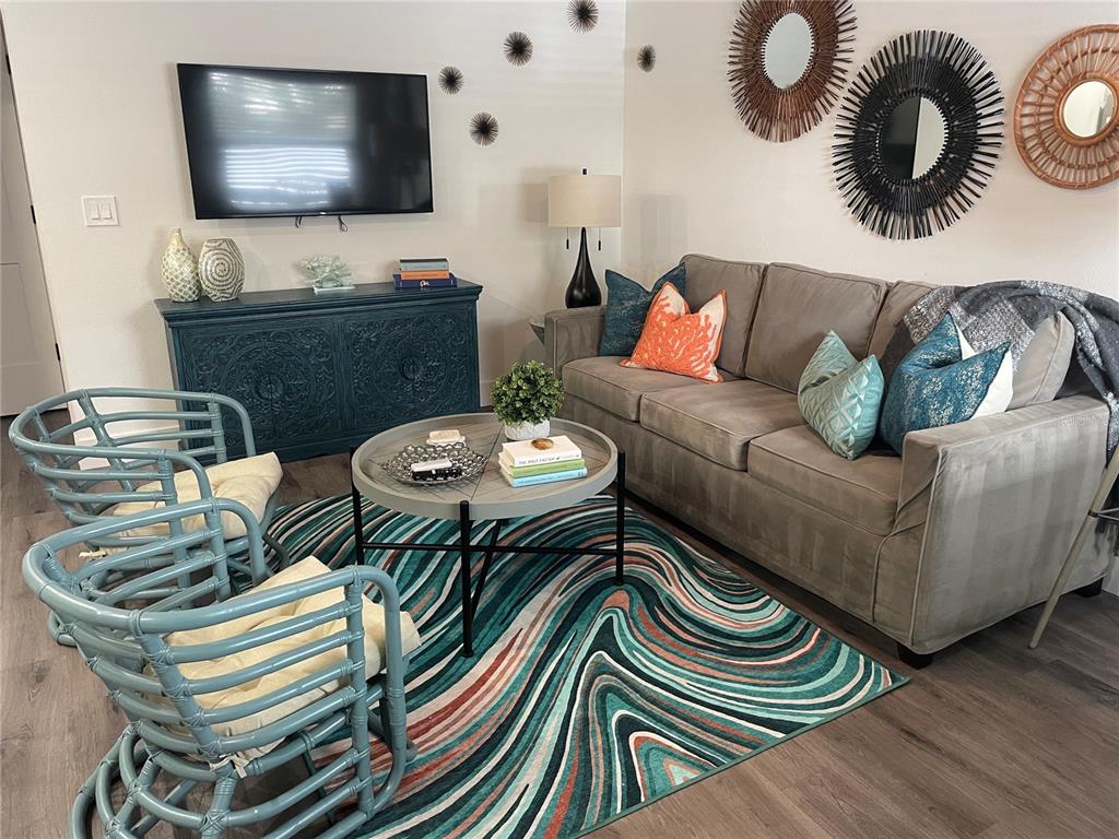 A living room features a grey sofa, two blue rattan chairs, and a patterned rug — 1912 MORRILL UNIT Lime, SARASOTA, FL