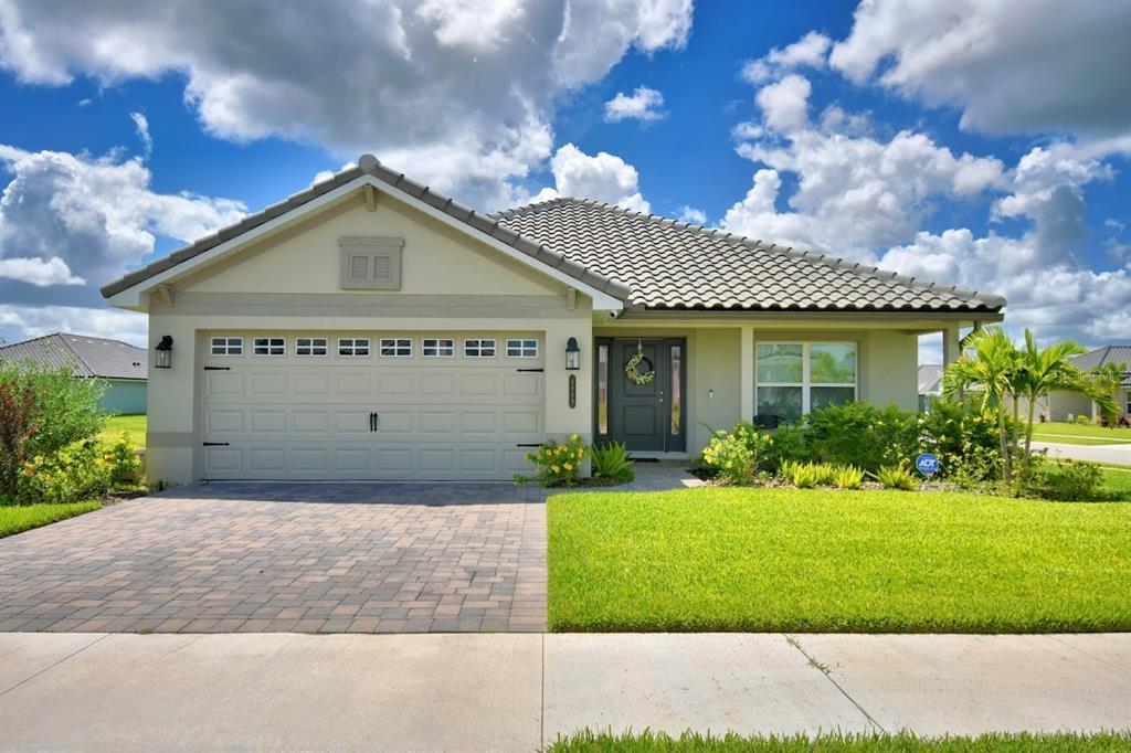 A single-story house with a beige stucco exterior, a tiled roof, and a paved driveway — 4669 GRANDVIEW GLEN DRIVE, AUBURNDALE, FL