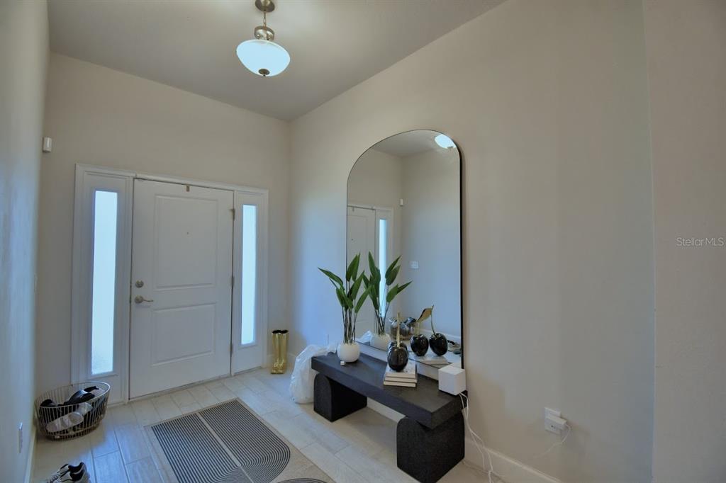 An entryway features a white door with sidelights, a large arched mirror, and a console table — 4669 GRANDVIEW GLEN DRIVE, AUBURNDALE, FL