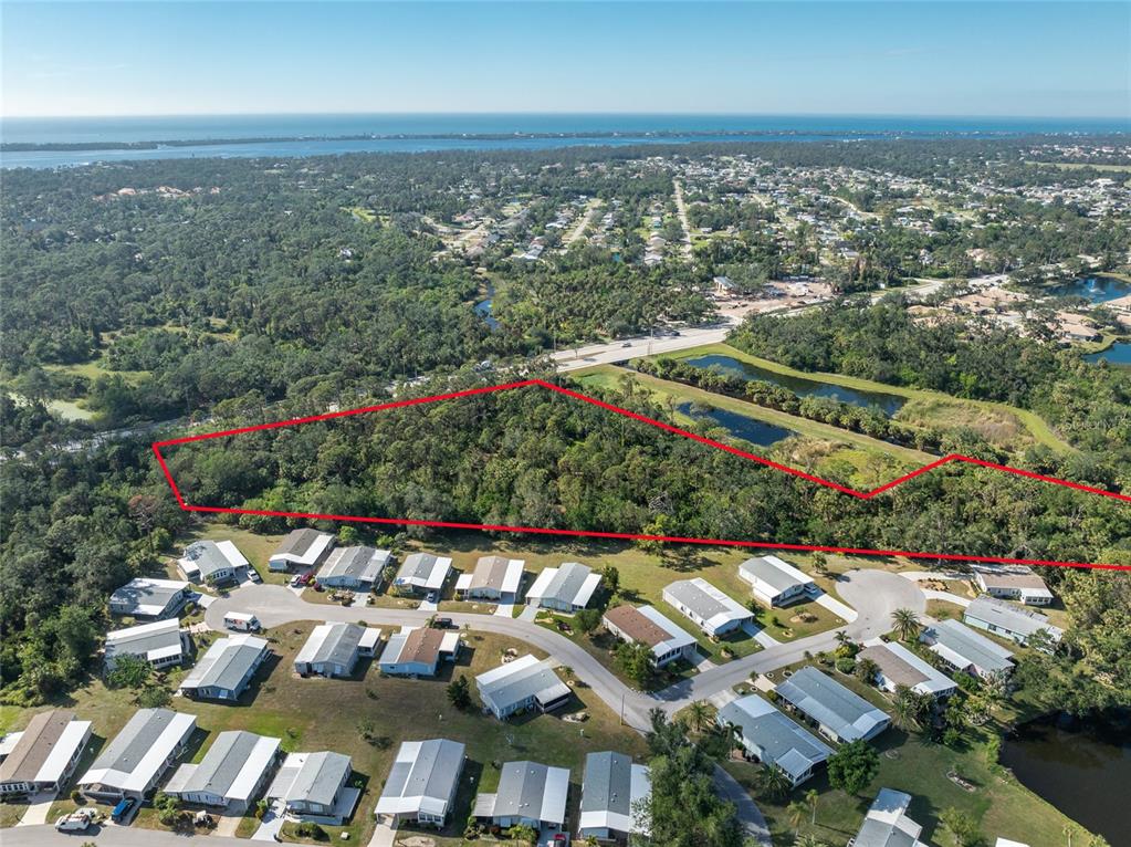 An aerial view shows a wooded lot outlined in red adjacent to a residential neighborhood — 0 N INDIANA AVENUE, ENGLEWOOD, FL