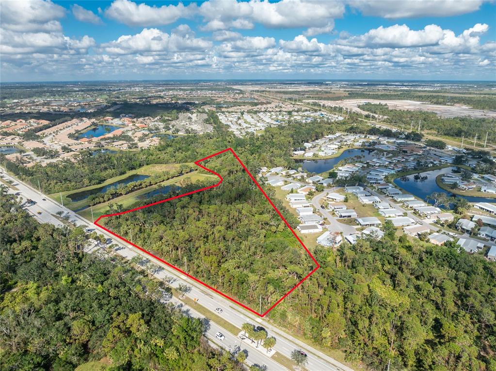 An aerial view shows a wooded plot of land outlined in red beside a road — 0 N INDIANA AVENUE, ENGLEWOOD, FL