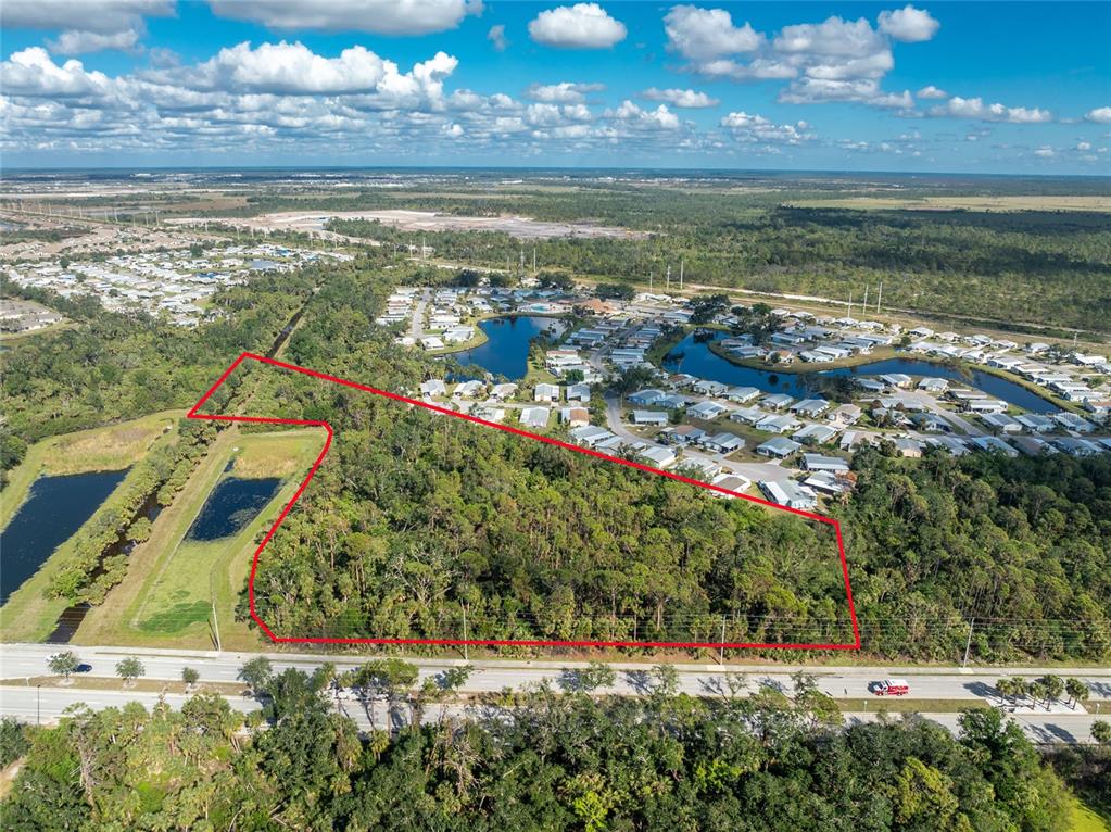 An aerial view shows a wooded, undeveloped lot outlined in red next to a residential neighborhood — 0 N INDIANA AVENUE, ENGLEWOOD, FL