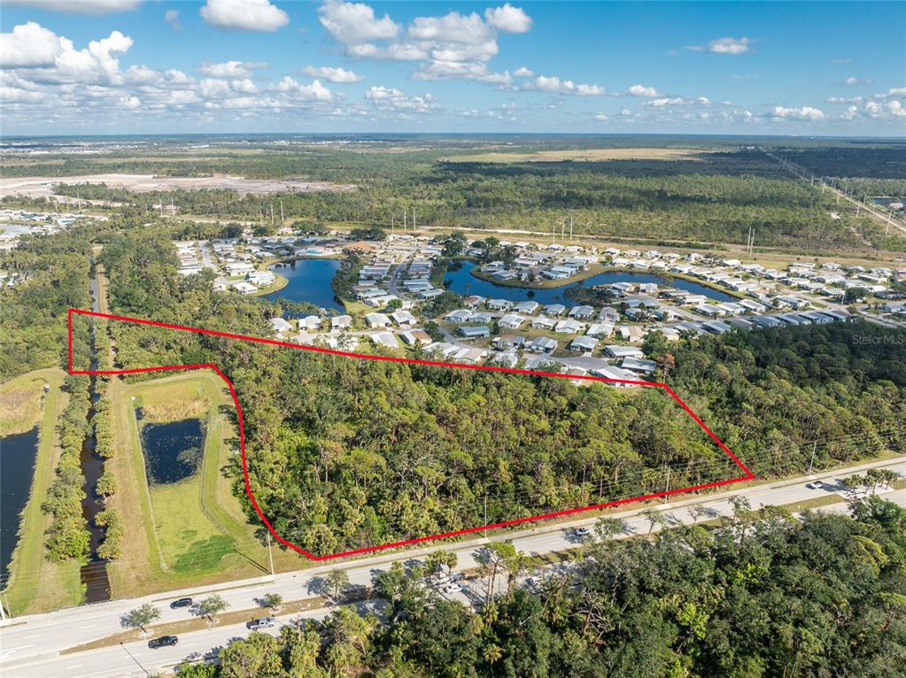 An aerial view shows a wooded, rectangular plot of land outlined in red near a road — 0 N INDIANA AVENUE, ENGLEWOOD, FL