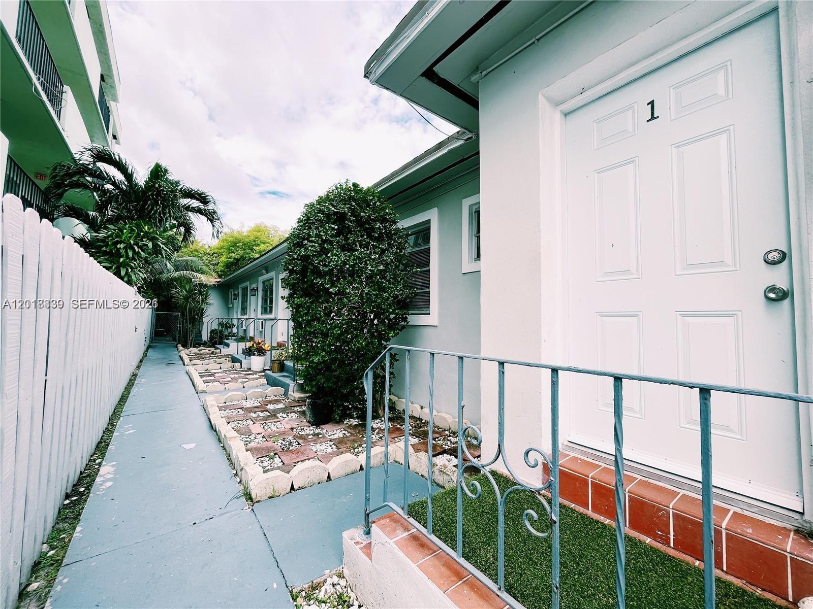 A white door labeled number one opens onto a small porch with a metal railing — 7630 Byron Ave, Miami Beach FL 33141, MIAMI BEACH, FL