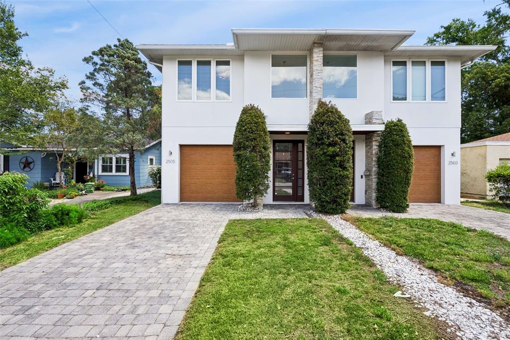 A two-story duplex with white stucco walls, wood-look garage doors, and a central entryway — 2505 DEPAUW AVENUE, ORLANDO, FL