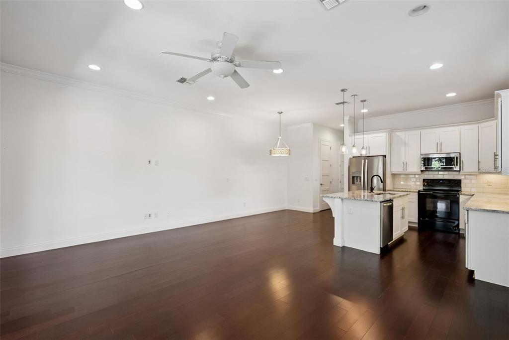 A spacious open-concept kitchen and living area featuring dark hardwood floors and white cabinetry — 2505 DEPAUW AVENUE, ORLANDO, FL