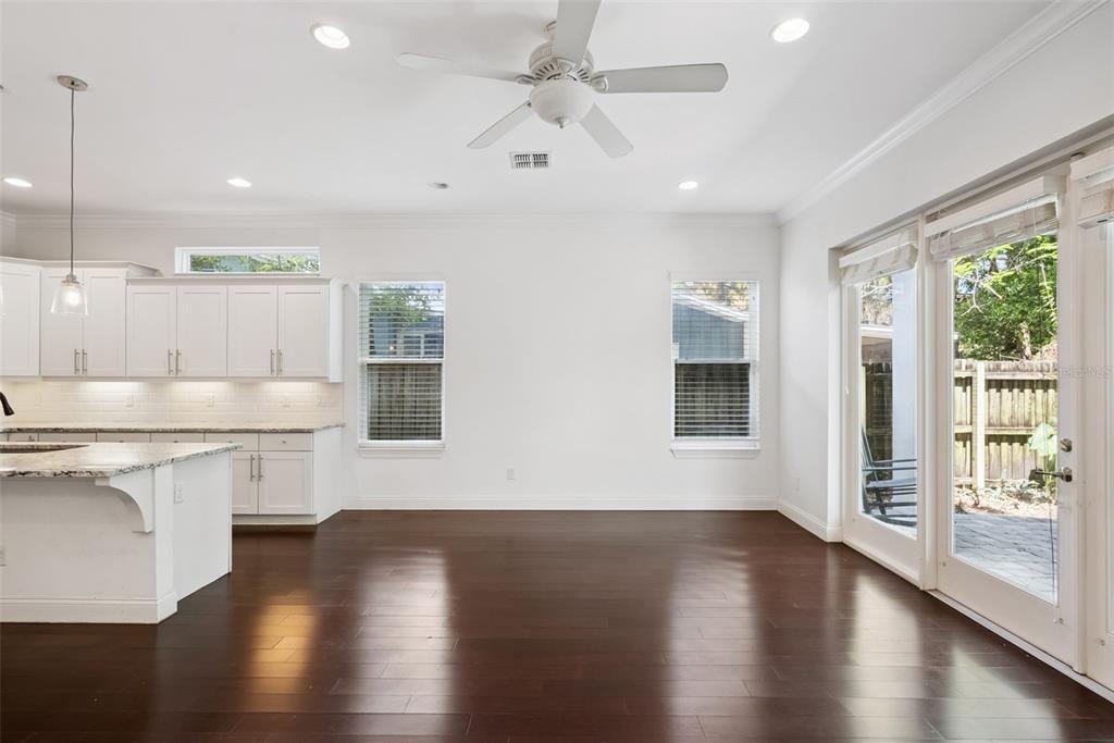 A bright dining area with dark hardwood floors, white cabinets, and glass sliding patio doors — 2505 DEPAUW AVENUE, ORLANDO, FL