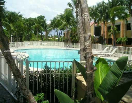 A round outdoor swimming pool is surrounded by a white fence and palm trees — 7961 SW 104 ST # B, Miami FL 33156, MIAMI, FL