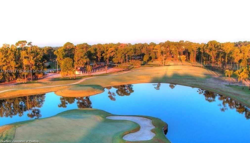 An aerial view of a golf course featuring a large pond and surrounding pine trees — 8525 BALADA DR, Sebring FL 33872, SEBRING, FL