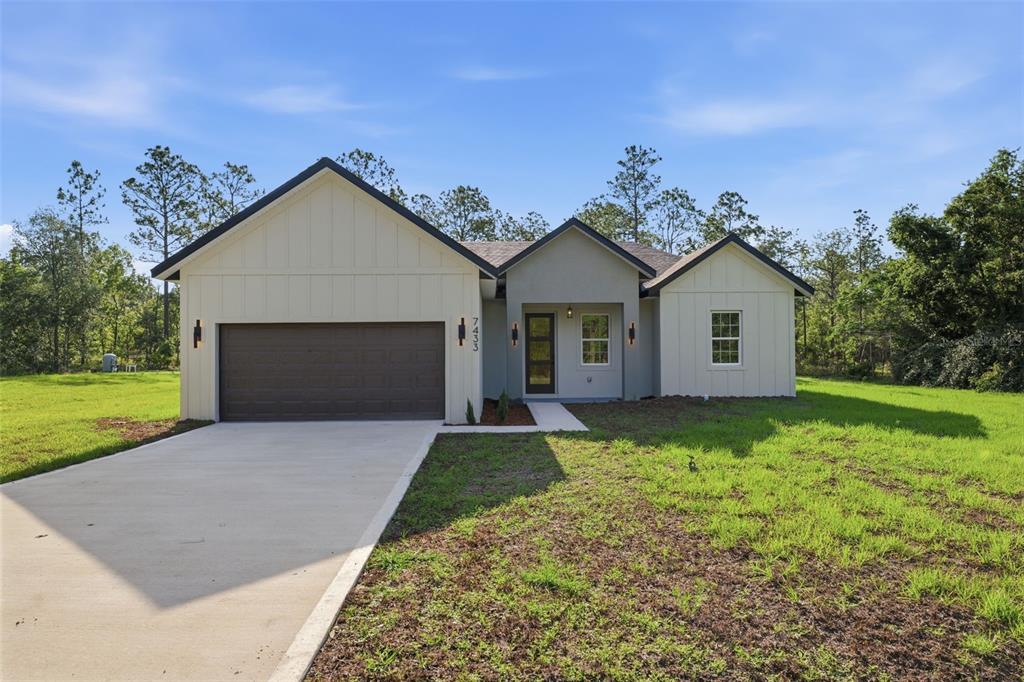 A single-story house with a garage, light-colored siding, and a concrete driveway — 7433 SW 138TH TERRACE, DUNNELLON, FL