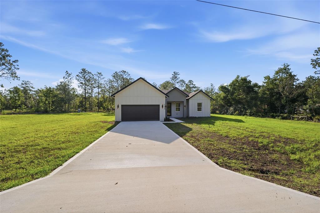 A single-story house with a concrete driveway and a two-car garage sits on a lot — 7433 SW 138TH TERRACE, DUNNELLON, FL