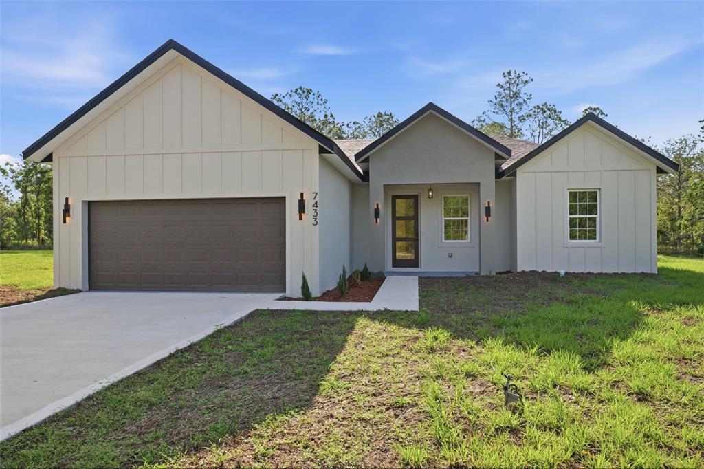 A single-story house with a brown garage door, light siding, and a concrete driveway — 7433 SW 138TH TERRACE, DUNNELLON, FL