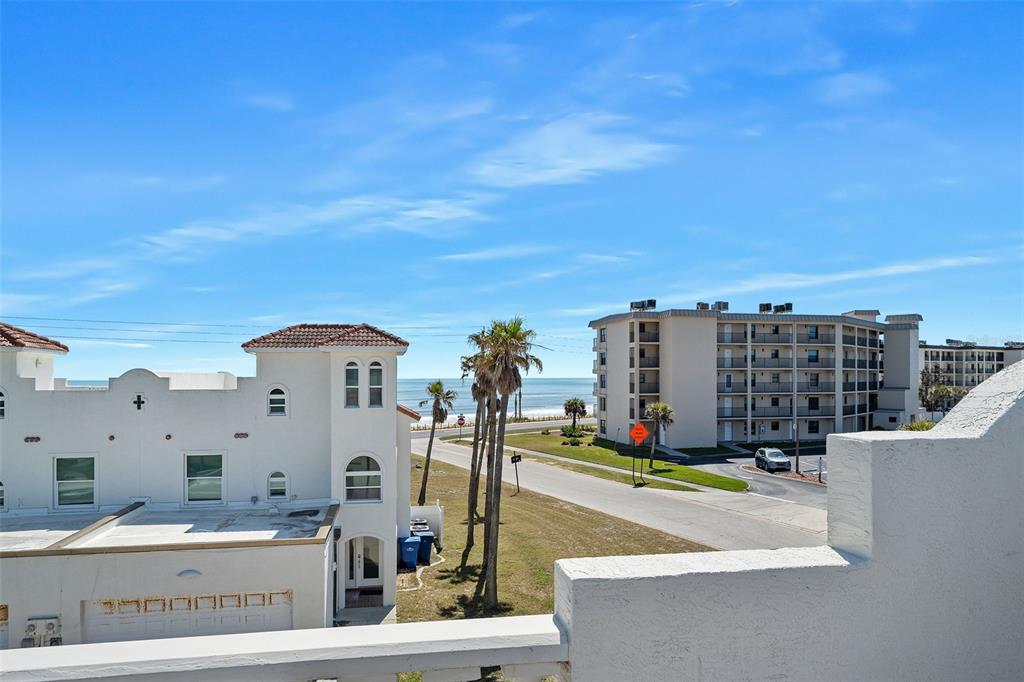 An elevated view shows a coastal street with palm trees, white buildings, and the ocean — 5 SUNNY BEACH DRIVE, ORMOND BEACH, FL