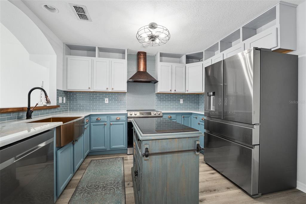 A kitchen features blue lower cabinets, white upper cabinets, a copper range hood, and stainless appliances — 5 SUNNY BEACH DRIVE, ORMOND BEACH, FL