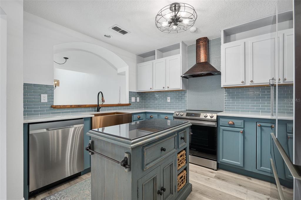 A kitchen features blue lower cabinets, white upper cabinets, a copper range hood, and island — 5 SUNNY BEACH DRIVE, ORMOND BEACH, FL
