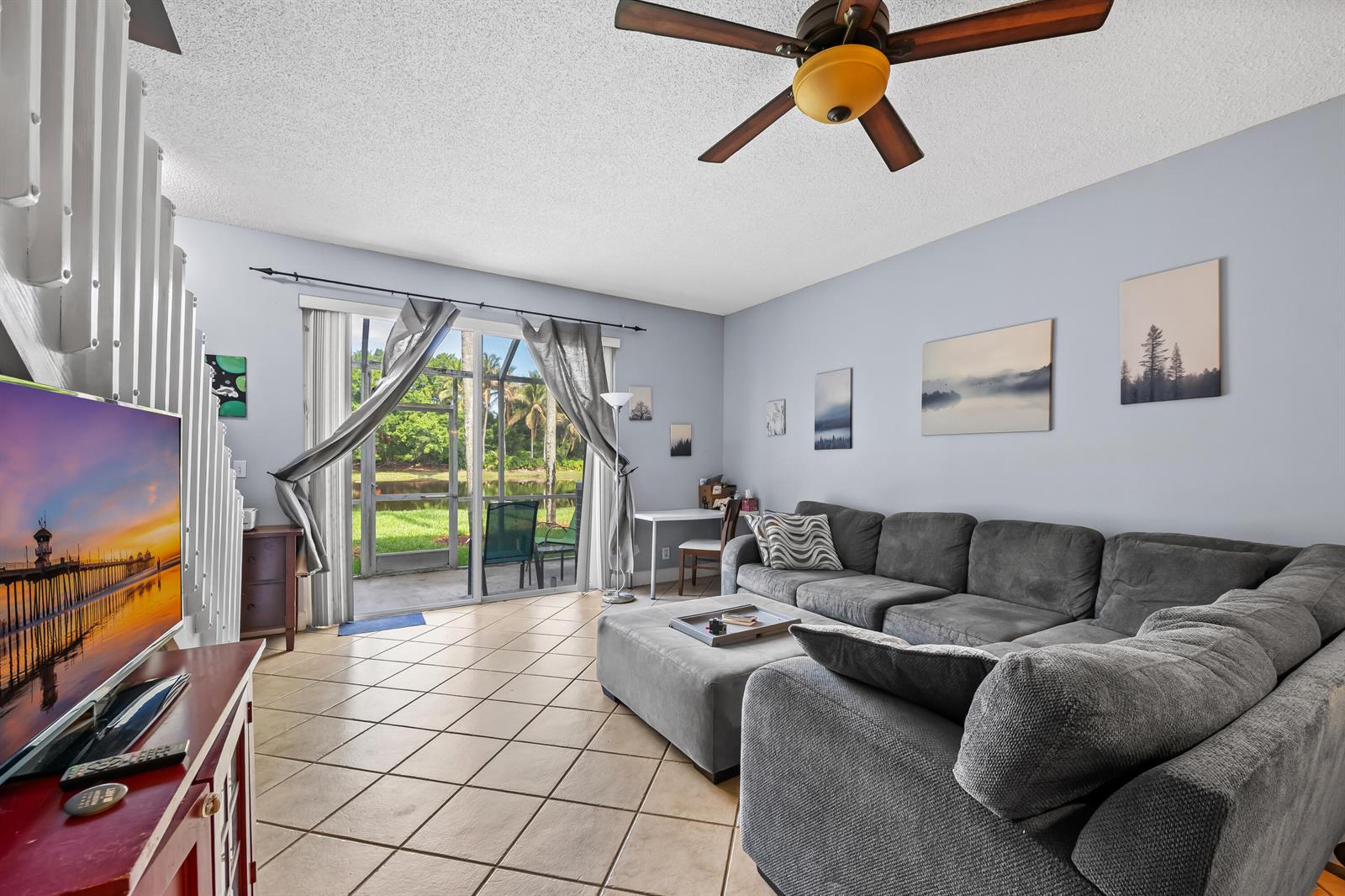 A living room features a grey sectional sofa, tile flooring, and sliding doors to a patio — 2185 Salerno Circle, Weston FL 33327, WESTON, FL