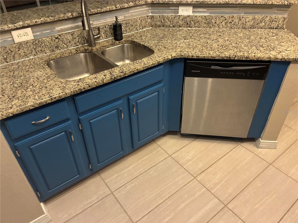 A kitchen features blue cabinets, granite countertops, a stainless steel sink, and a dishwasher — 3315 PARKCHESTER SQUARE BOULEVARD UNIT 206, ORLANDO, FL
