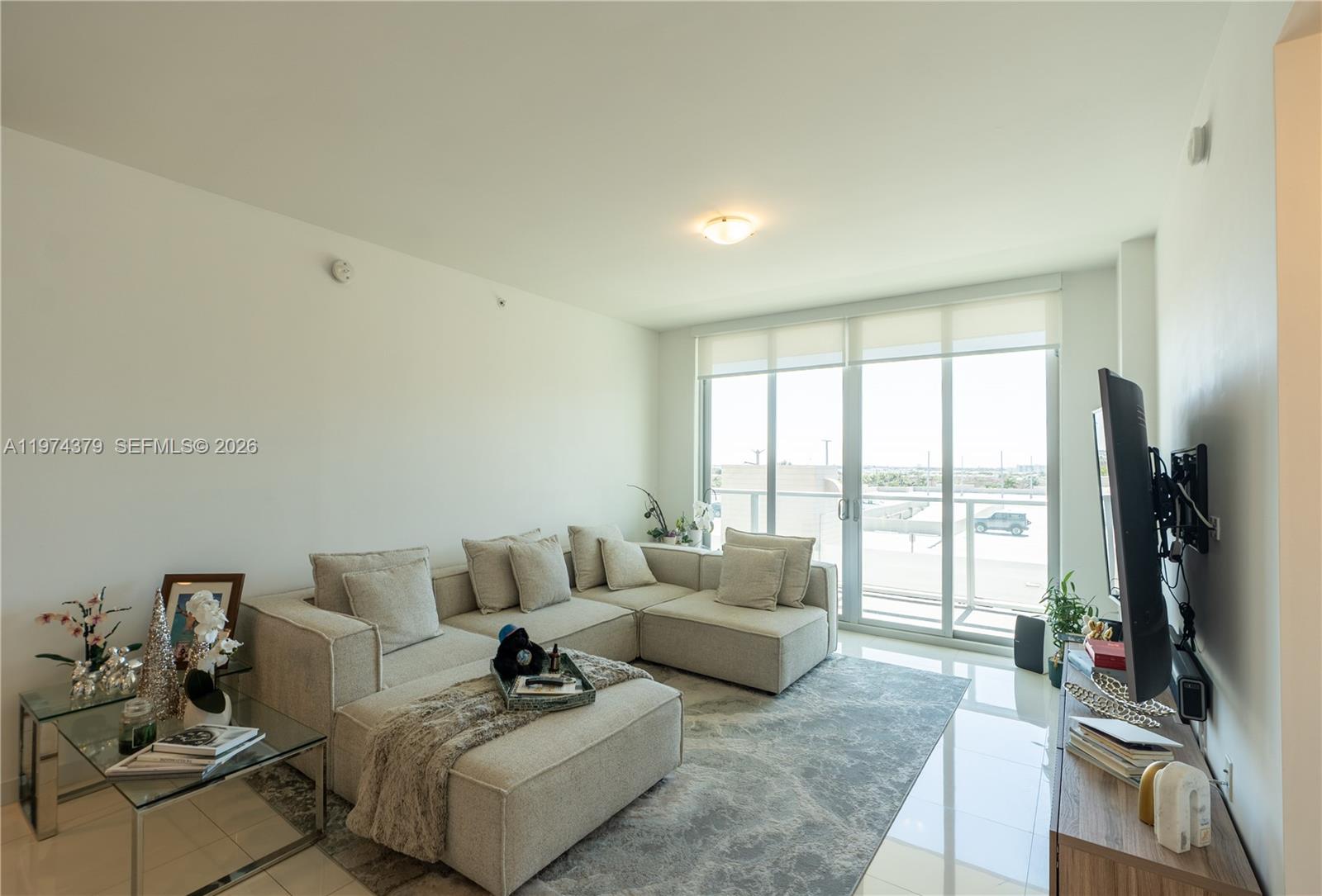 A living room features a beige sectional sofa, a glass side table, and floor-to-ceiling windows — 7751 NW 107th Ave # 721, Doral FL 33178, DORAL, FL