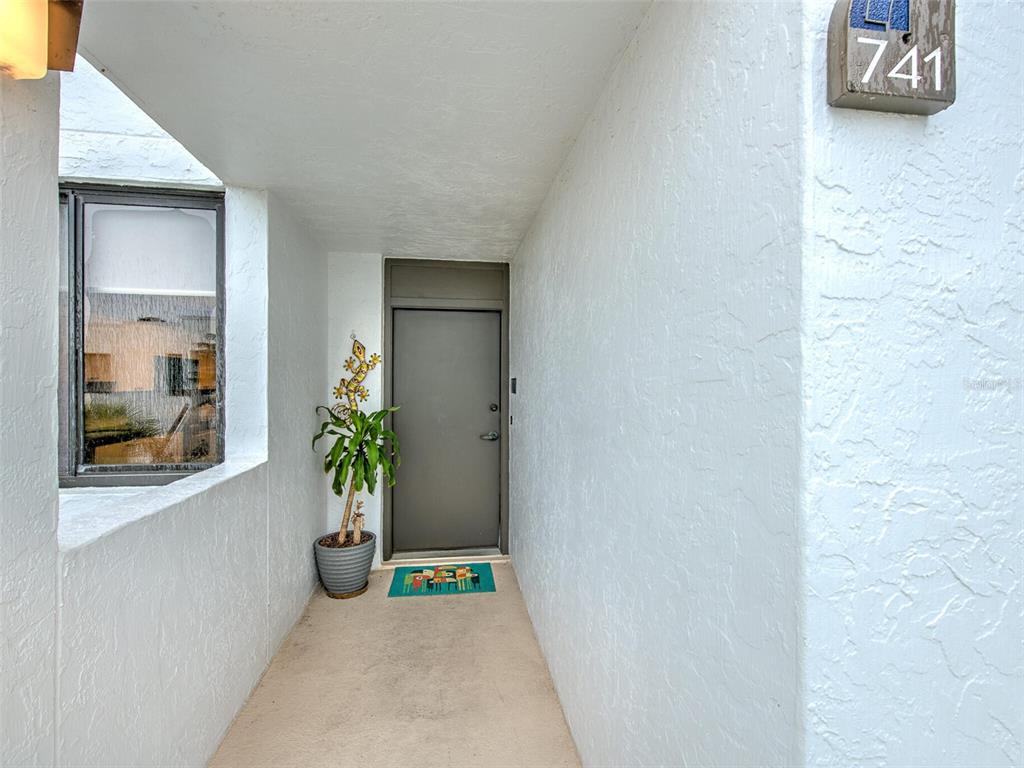 A covered entryway features a gray door, a potted plant, and a house number 741 — 741 BAYPORT WAY UNIT 741, LONGBOAT KEY, FL