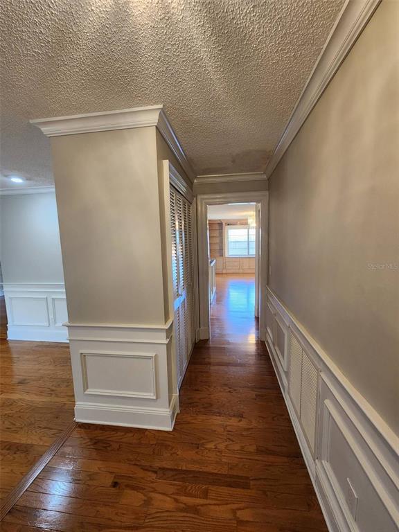 A hallway with hardwood floors, white wainscoting, and a louvered closet door leads to another room — 549 BURLINGTON AVENUE NE, PALM BAY, FL