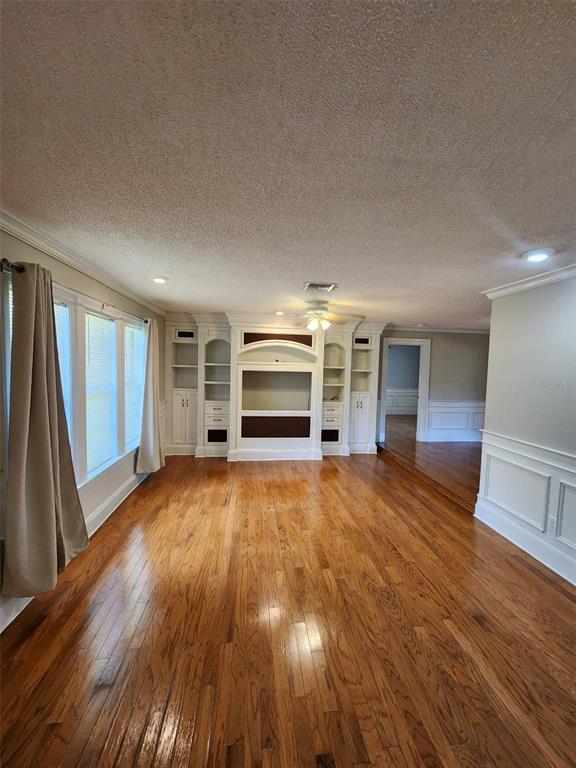 A living room with hardwood floors, a built-in entertainment center, and wainscoting on the walls — 549 BURLINGTON AVENUE NE, PALM BAY, FL