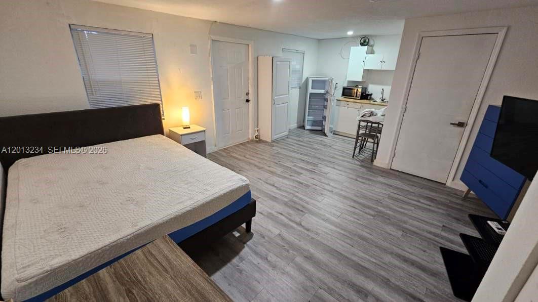This studio apartment features a bed, a small kitchenette, and light-colored wood-look flooring — 4201 SW 32nd Dr # 1, West Park FL 33023, WEST PARK, FL