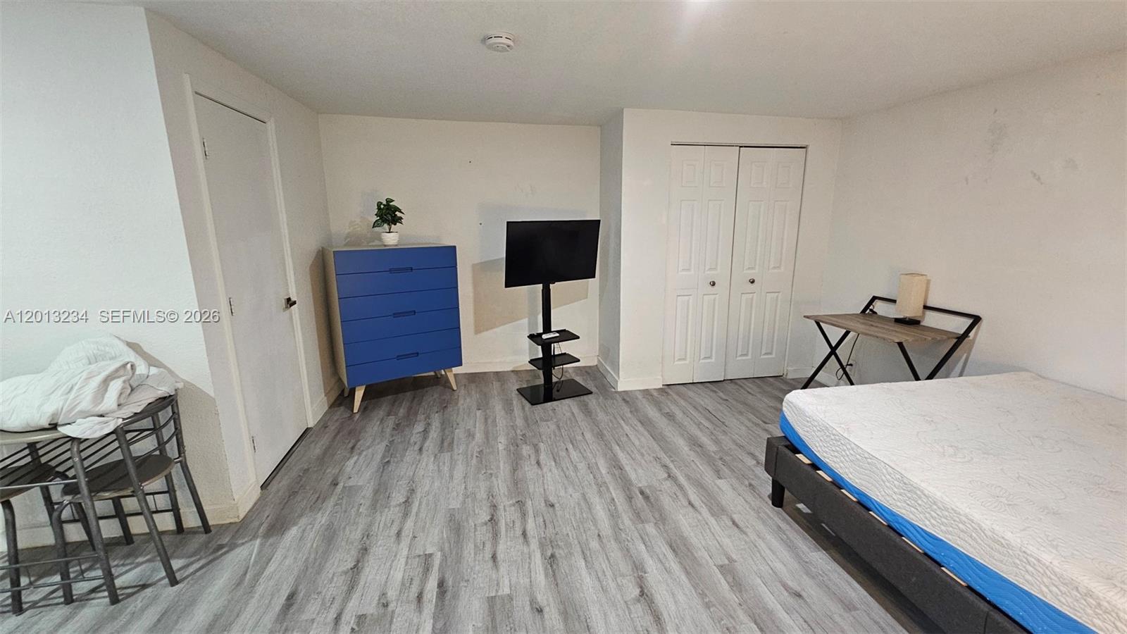 A bedroom features gray wood-look flooring, a blue dresser, a television stand, and a bed — 4201 SW 32nd Dr # 1, West Park FL 33023, WEST PARK, FL