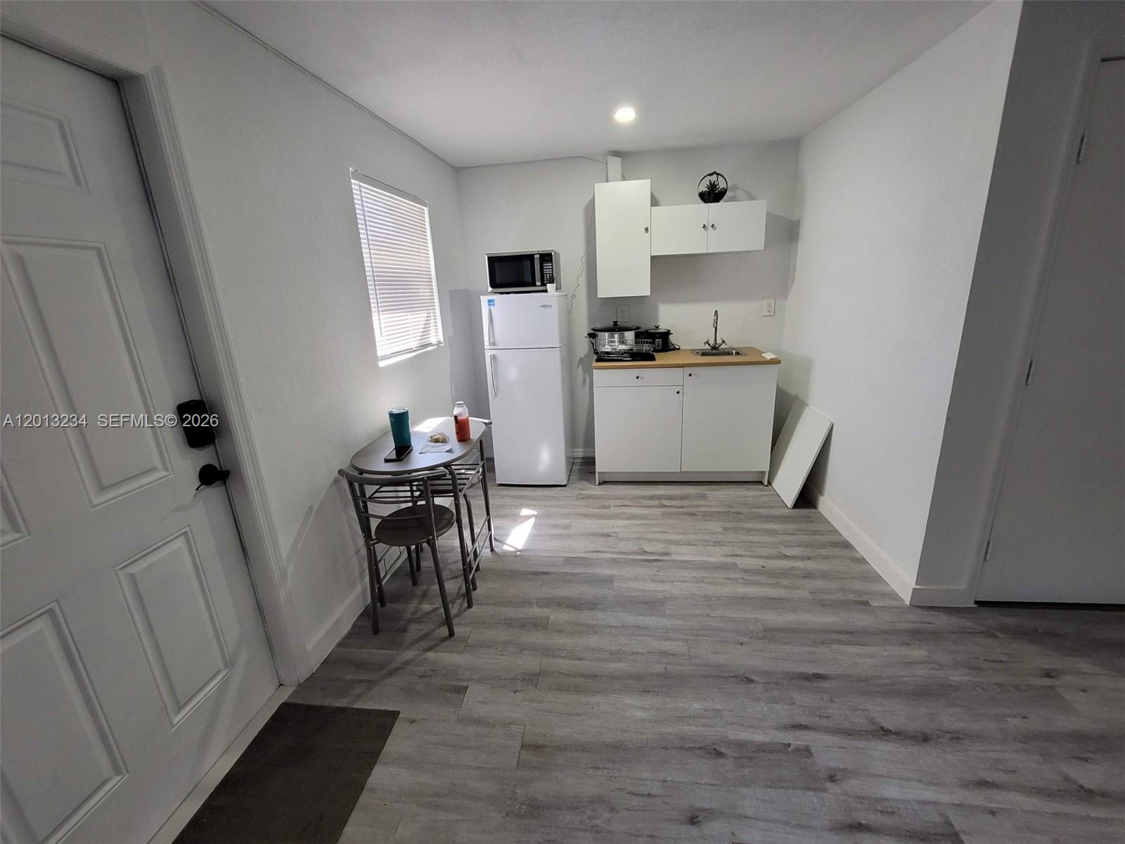 A small kitchen area features white cabinets, a refrigerator, a microwave, and a dining table — 4201 SW 32nd Dr # 1, West Park FL 33023, WEST PARK, FL