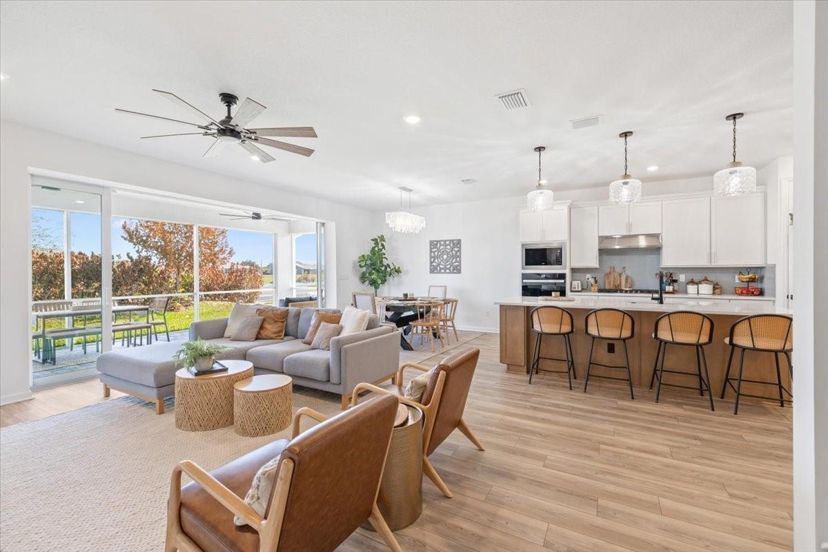 A living room with a gray sectional sofa opens to a screened-in patio and lake view — 4597 Nautilus Circle, Vero Beach FL 32967, VERO BEACH, FL