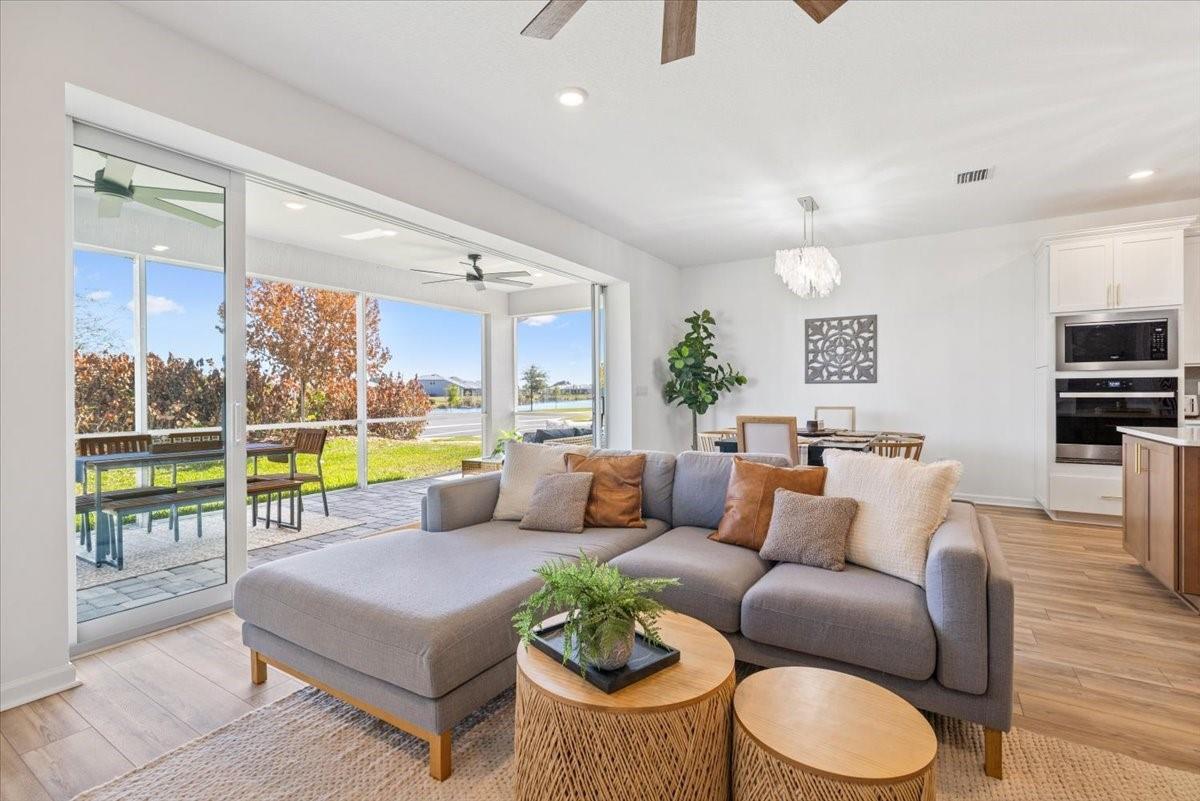 An open-concept living room and kitchen featuring light wood floors, white cabinetry, and sliding doors — 4597 Nautilus Circle, Vero Beach FL 32967, VERO BEACH, FL