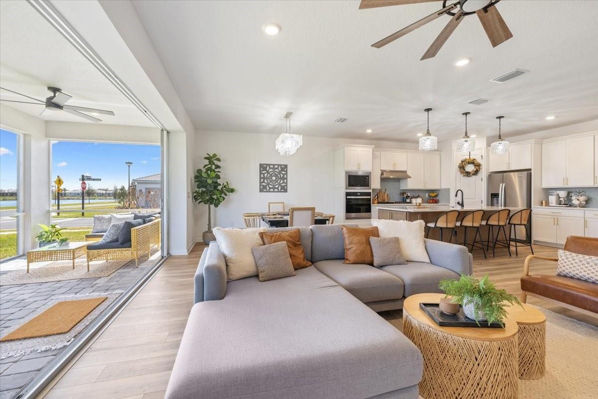 An open-concept living room and kitchen featuring a sectional sofa, dining area, and sliding glass doors — 4597 Nautilus Circle, Vero Beach FL 32967, VERO BEACH, FL