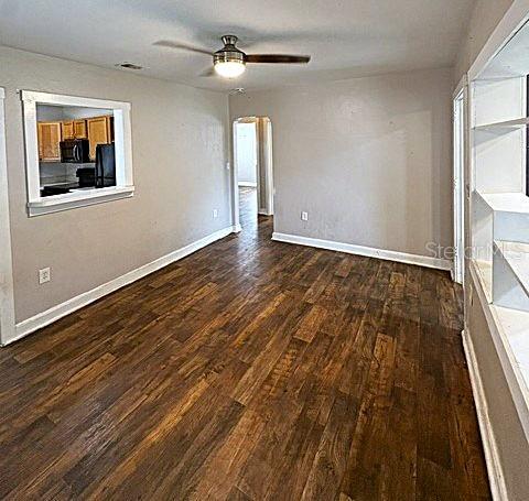 A room with wood-look flooring, a ceiling fan, and a pass-through window to the kitchen — 1002 OAKHILL STREET, LAKELAND, FL