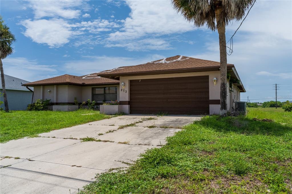 A single-story house with a brown roof, garage, and overgrown lawn under a blue sky — 273 ROTONDA CIRCLE, ROTONDA WEST, FL