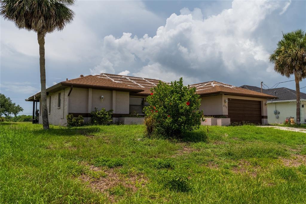 A single-story house with a brown roof and a garage sits on a grassy lot — 273 ROTONDA CIRCLE, ROTONDA WEST, FL